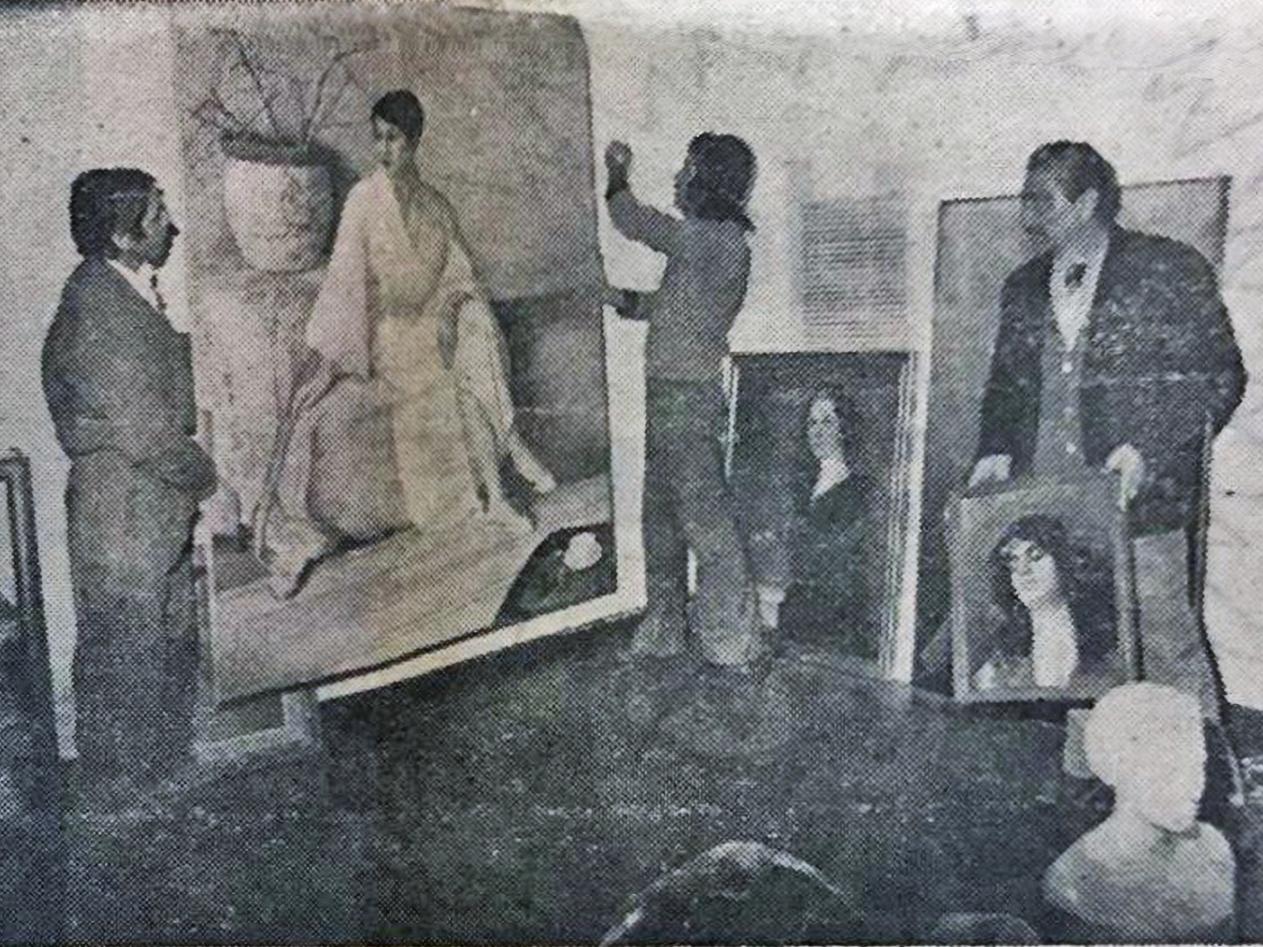 Fotografía en blanco y negro de tres hombres manipulando pinturas