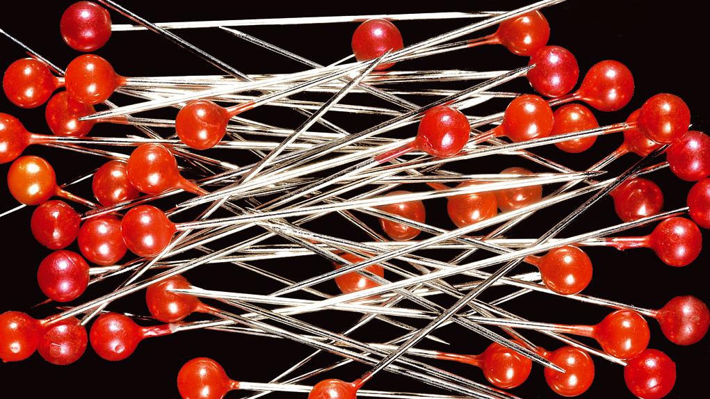 Fotografía de un puñado de alfileres con cabecilla roja