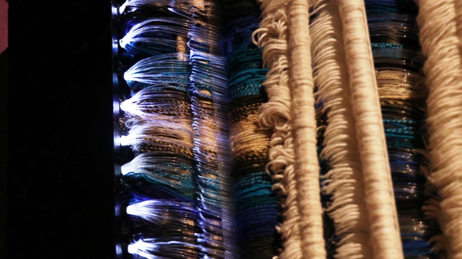 Detalle de un telar con fibras ópticas e hilos.