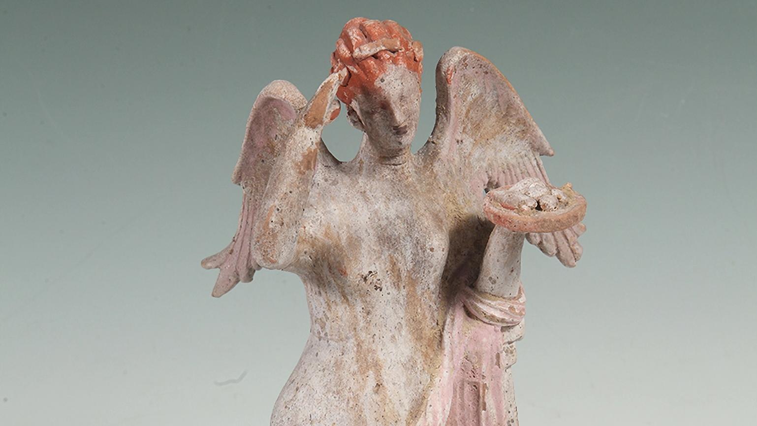 Fotografía de estatuilla antigua representando una figura alada