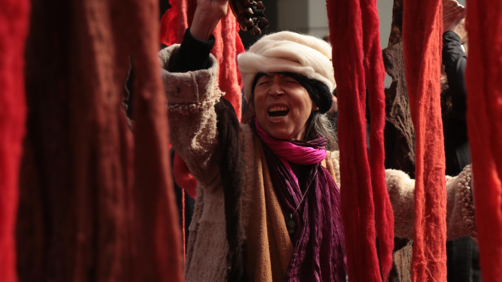 Mujer mayor riendo alrededor de telas de color rojo y naranja