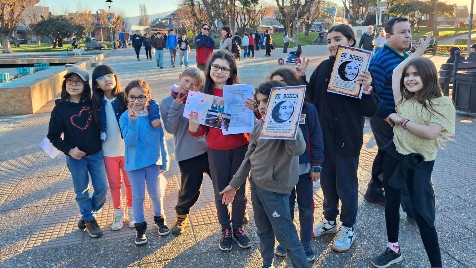Fotografía de niñas y niños levantando carteles con el rostro de Gabriela Mistral