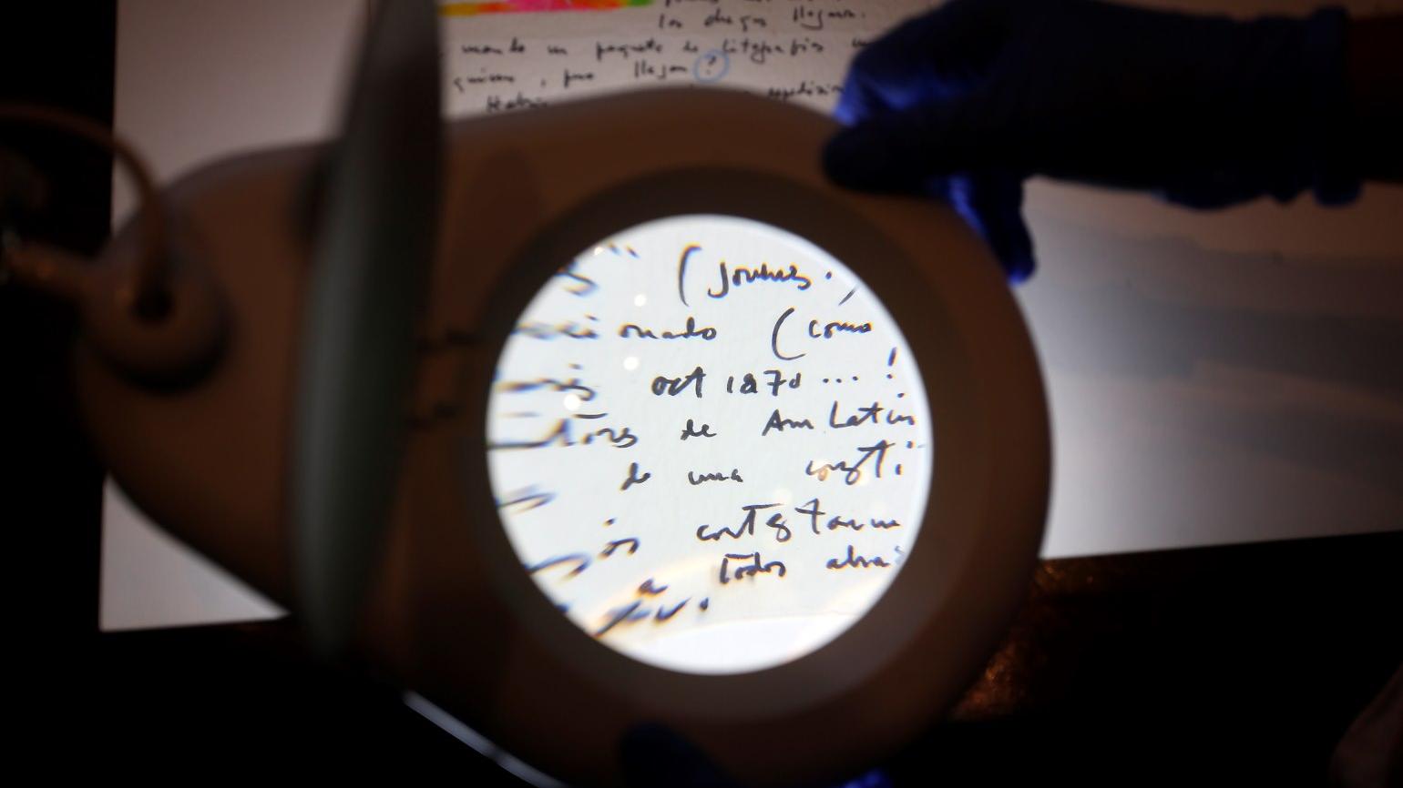 Fotografía de una persona leyendo un documento a través de una lupa