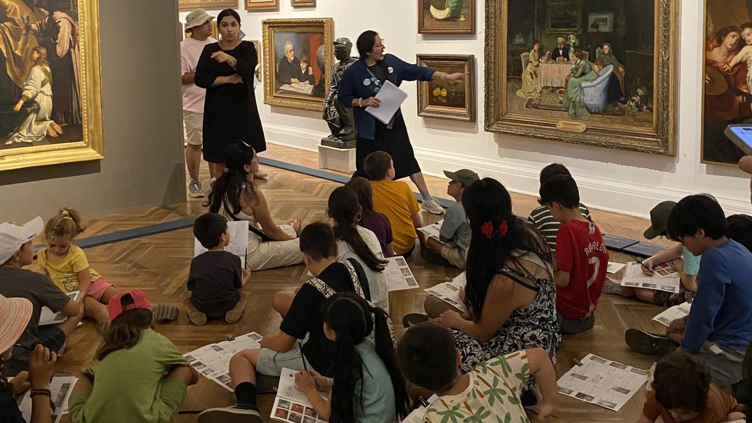 Grupo de niños sentados en piso en una sala de exposición