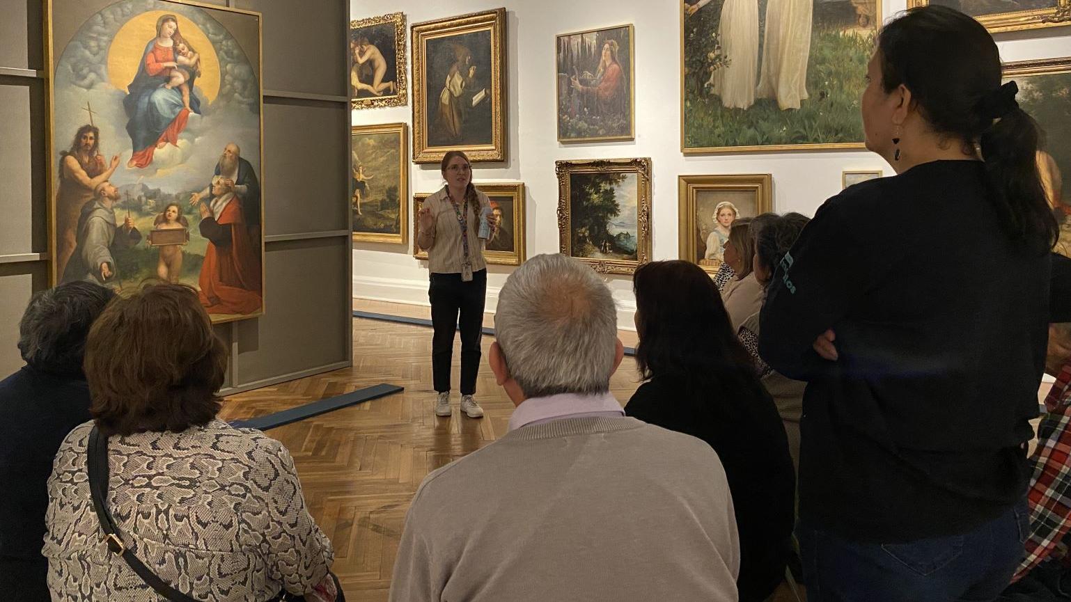 Grupo de personas observando pinturas en una exposición