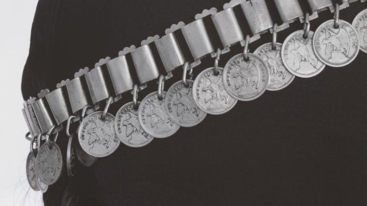 Silueta femenina en negro, utilizando joyería tradicional mapuche