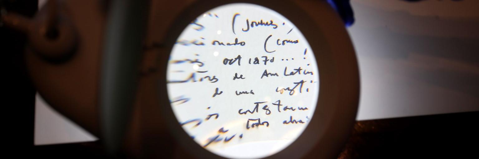 Fotografía de una persona leyendo un documento a través de una lupa