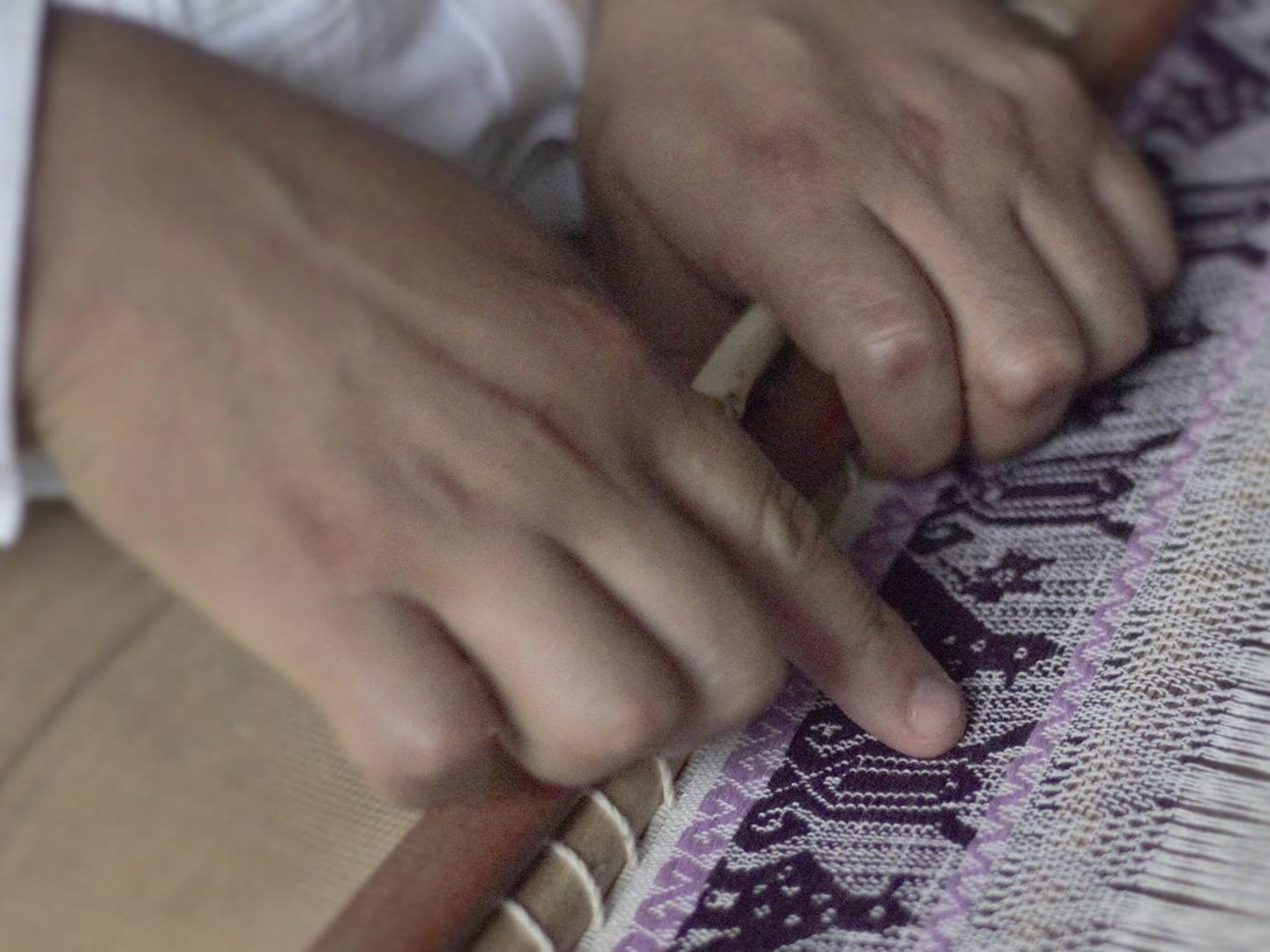 Manos tejiiendo en telar