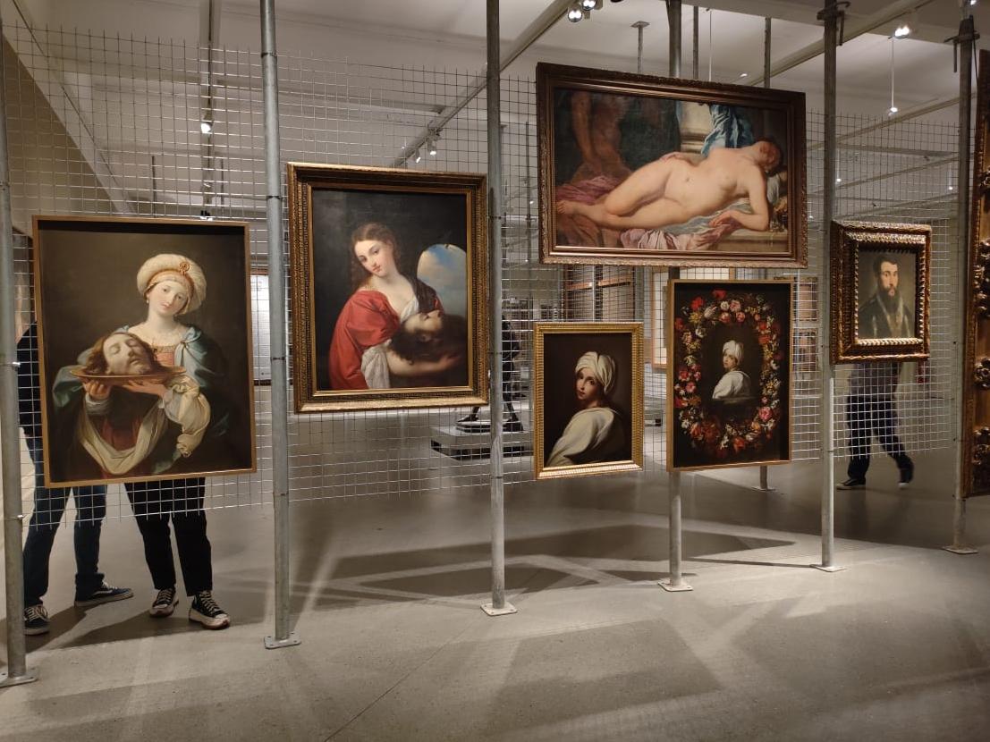 Exposición con pinturas colgadas de una rejilla