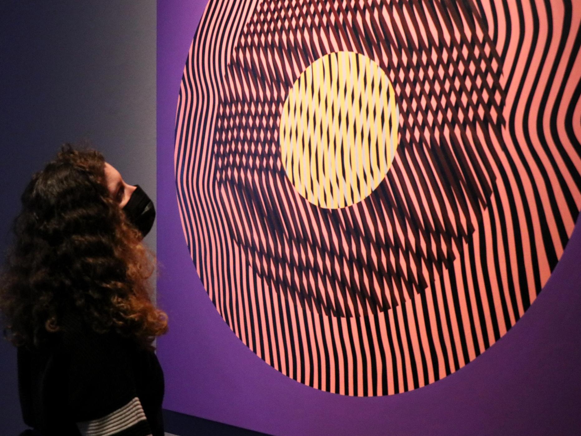 Mujer mirando obra de arte geométrico en tonos púrpura