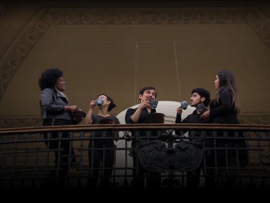 Personas conversando con tazas en uno de los balcones del Museo