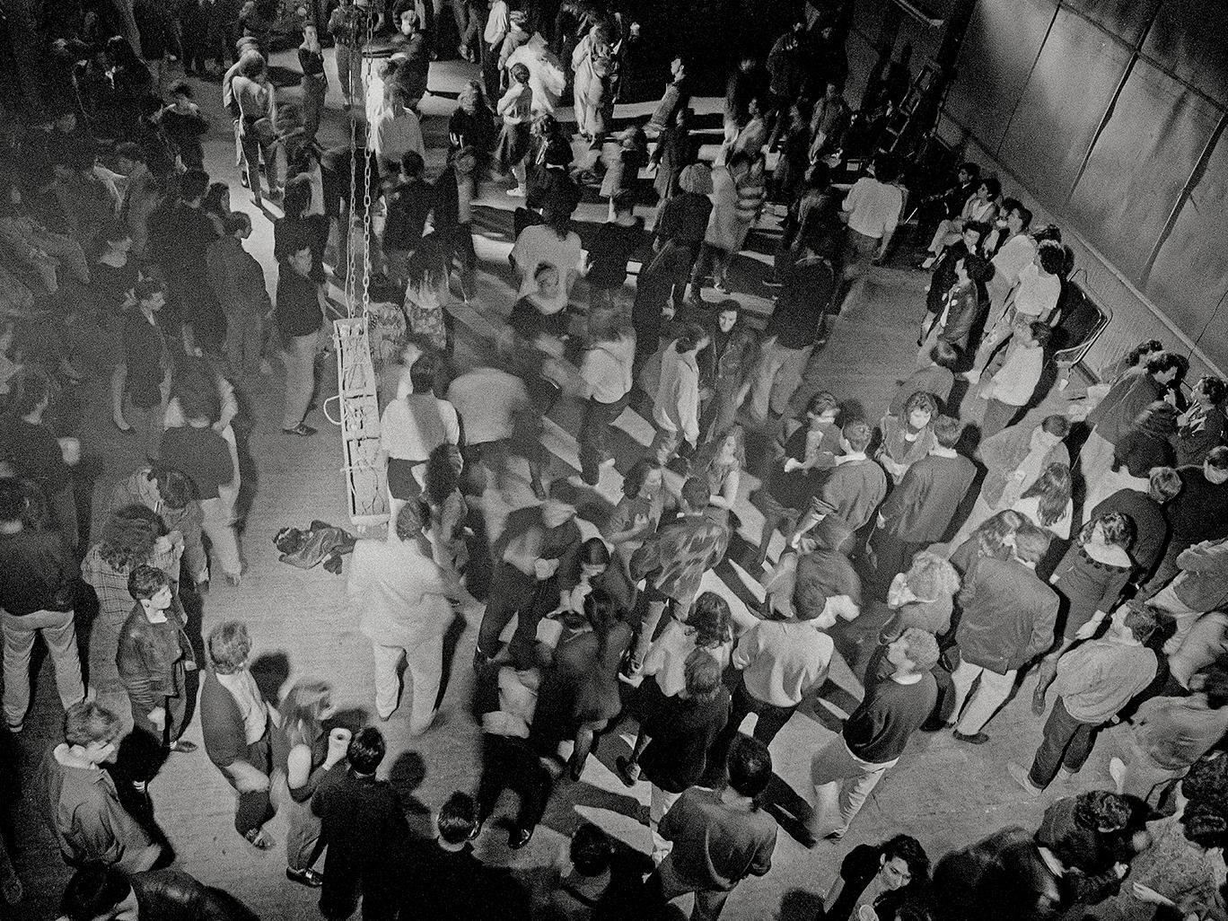 Imagen en blanco y negro de grupo de personas reunidas en un galpón