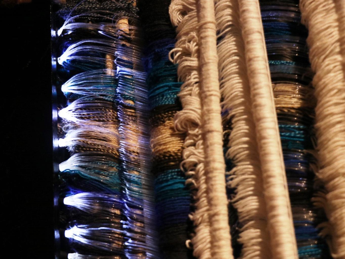 Detalle de un telar con fibras ópticas e hilos.
