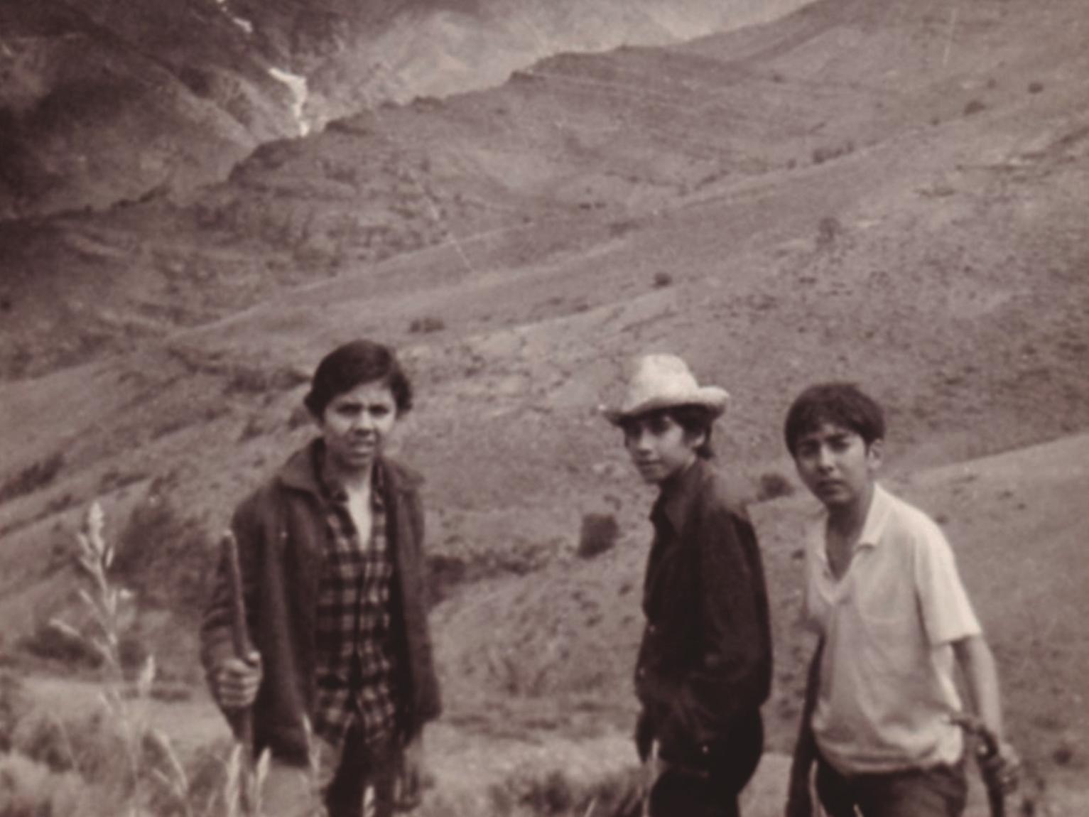 Fotografía de tres niños posando en un paisaje cordillerano