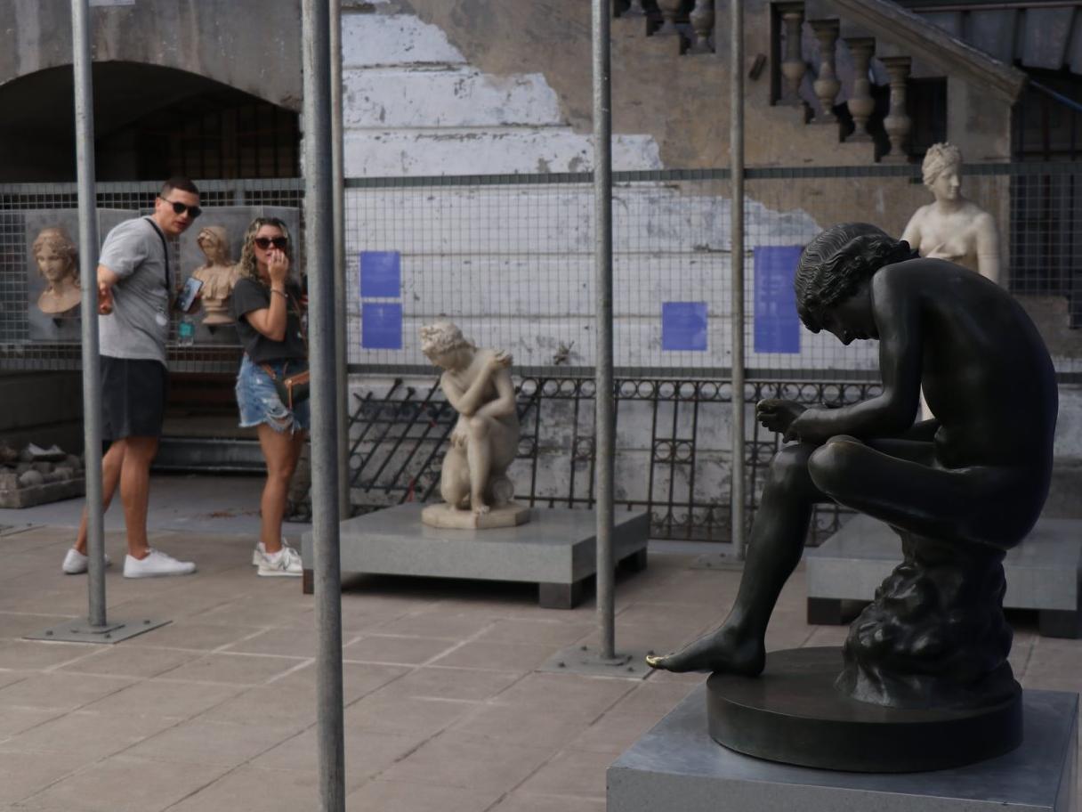 Imagen de dos personas observando tres esculturas en un patio