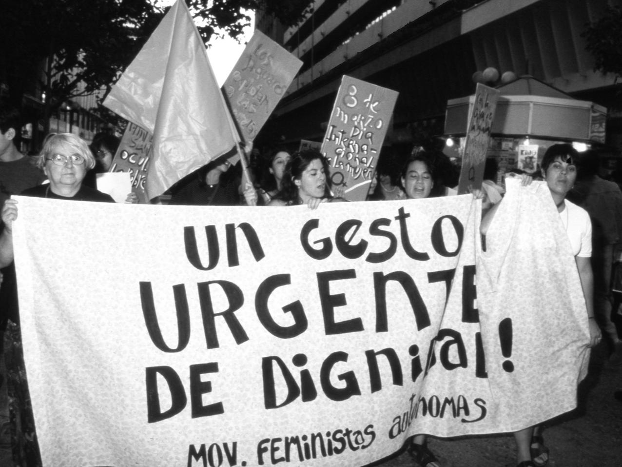 Grupo de mujeres sosteniendo un lienzo y participando en una marcha