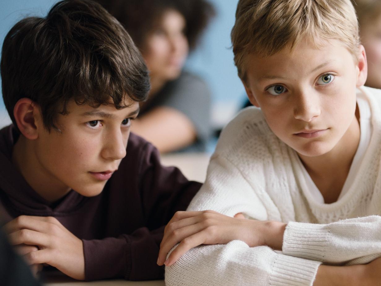 Fotografía de dos niños y una mujer, tendidos en el pasto riendo