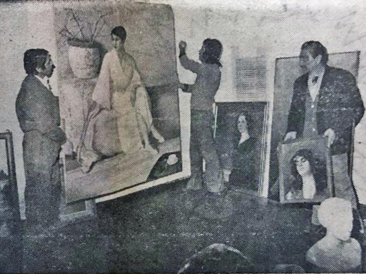 Fotografía en blanco y negro de un grupo de hombres montando cuadros para una exposición