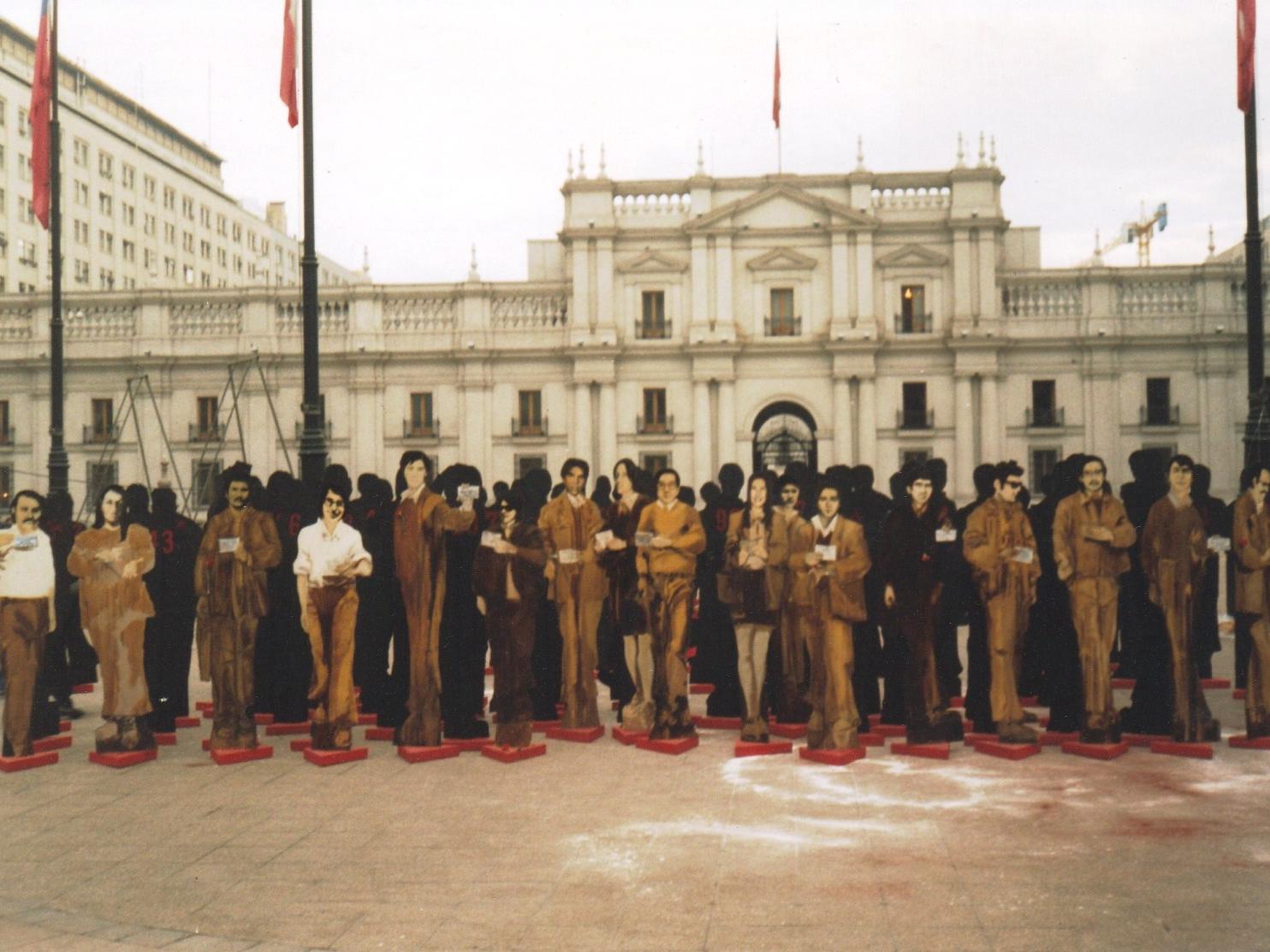 Fotografía de siluetas de personas hechas en cartón, frente al Palacio de La Moneda.