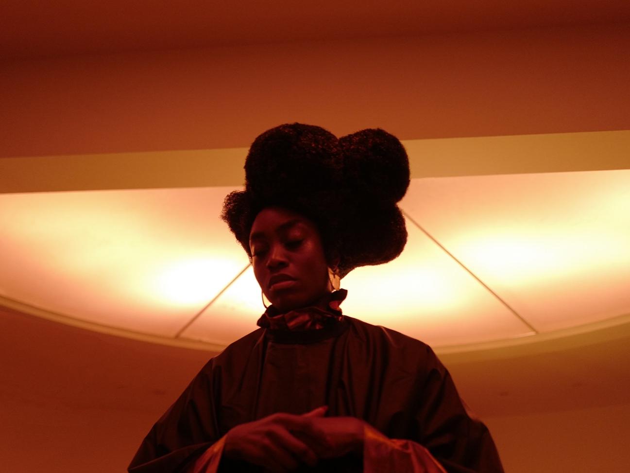 Fotografía de una mujer afrodescendiente sobre un fondo anaranjado