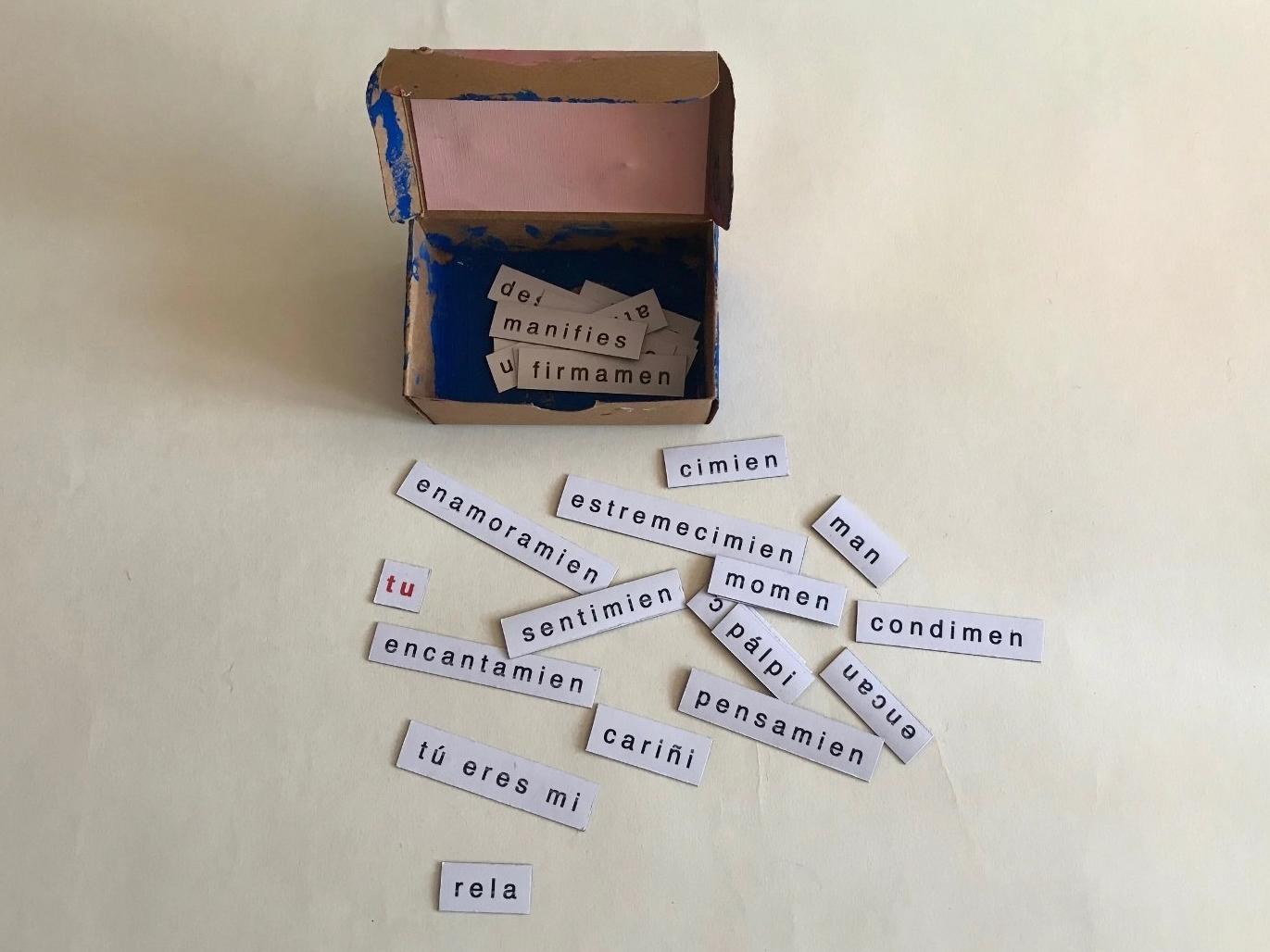 Caja de fósforos intervenida, con papeles a su alrededor que tienen diversas palabras escritas