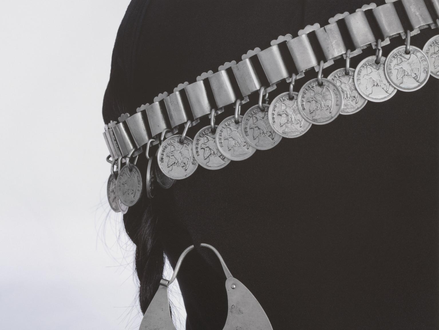 Fotografía de una mujer cubierta con ropas negras, utilizando ornamentos mapuches
