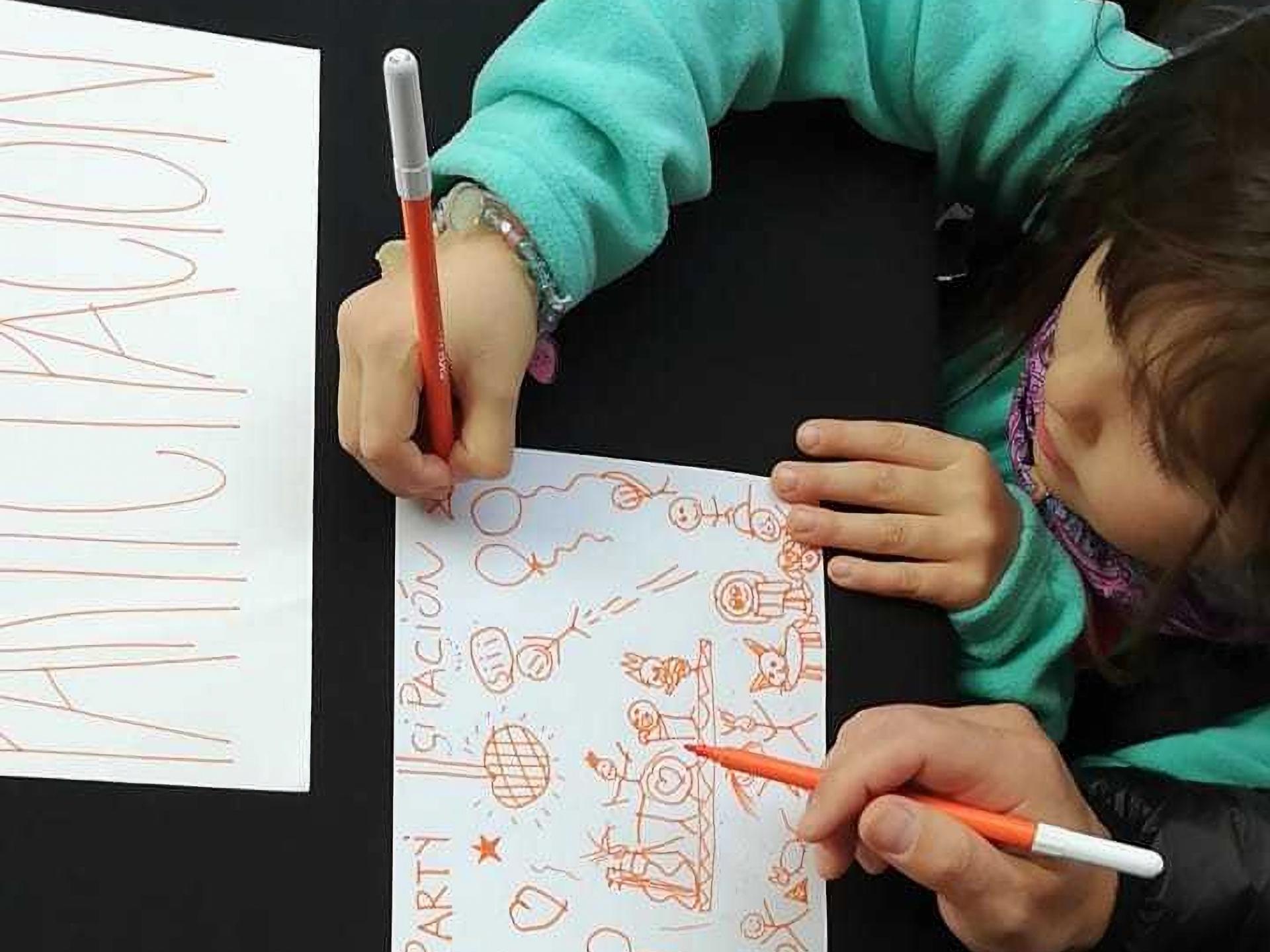 Fotografía de niña dibujando sobre un papel