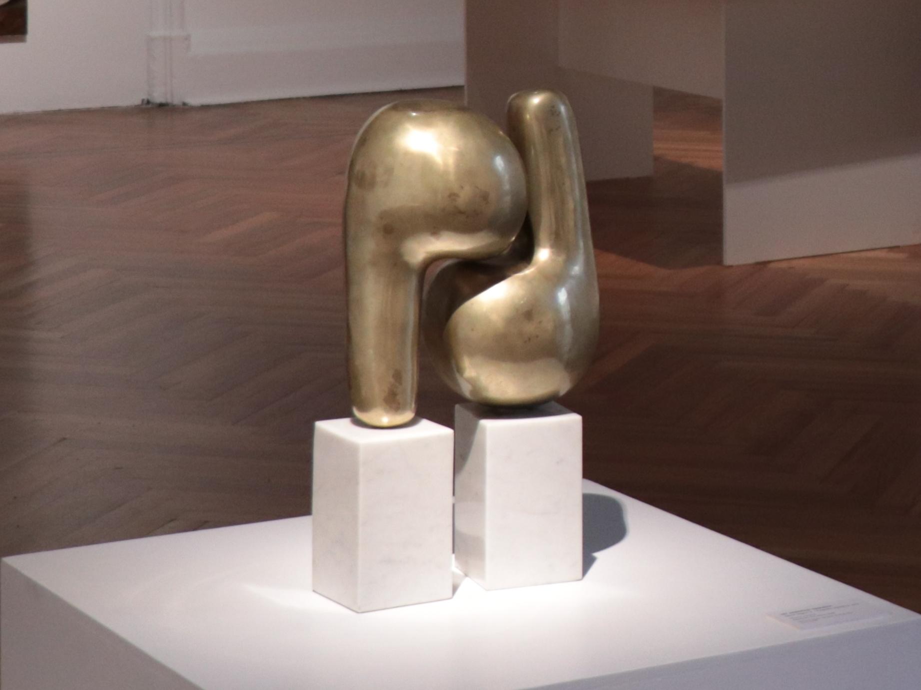 Fotografía de una escultura en metal dorado, con formas curvas