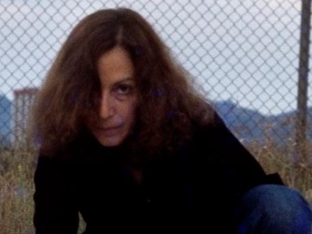 Fotografía de una mujer agachada sobre el pavimento, con una huincha blanca