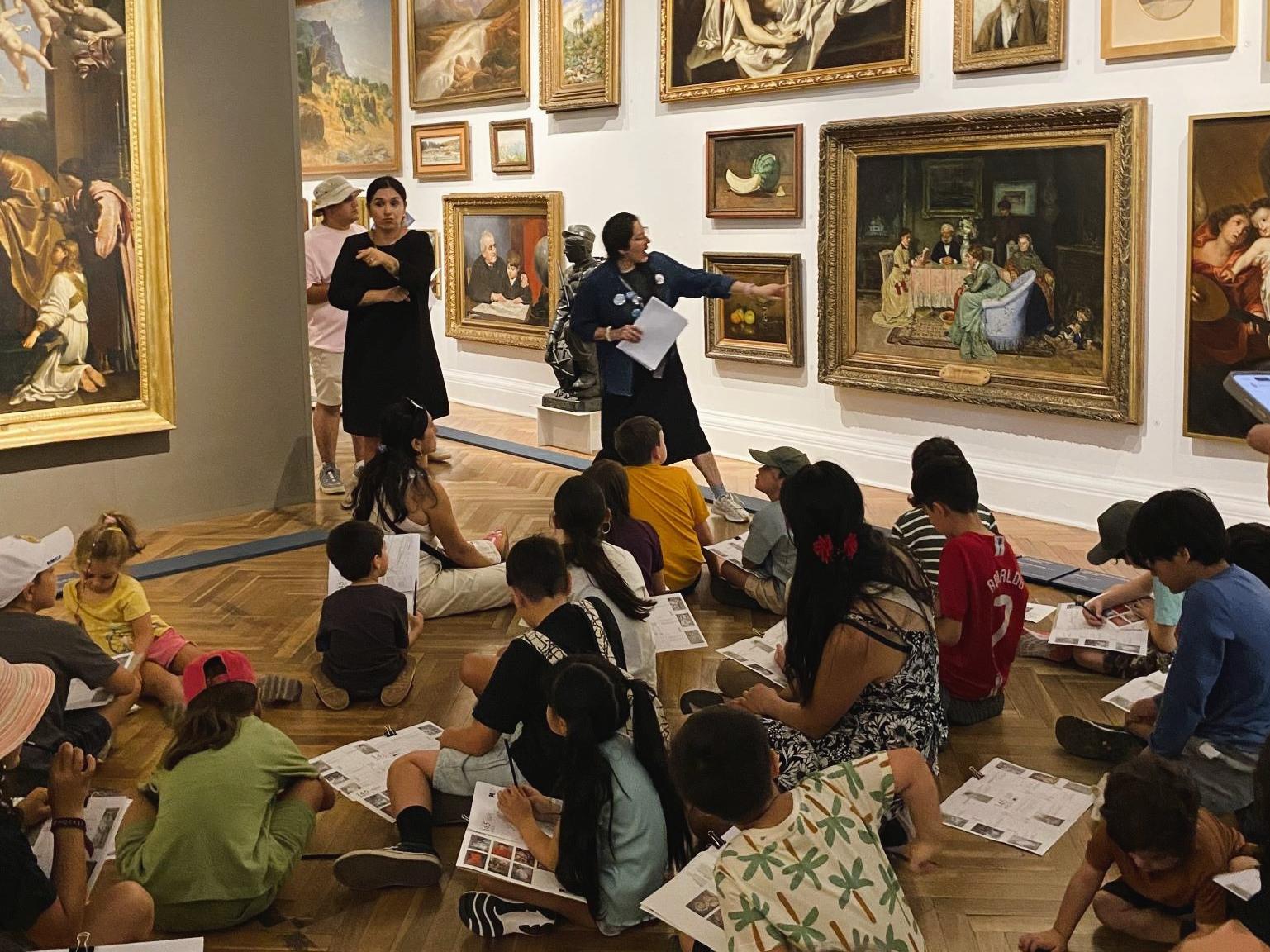 Grupo de niños sentados en el piso de una sala de exposición