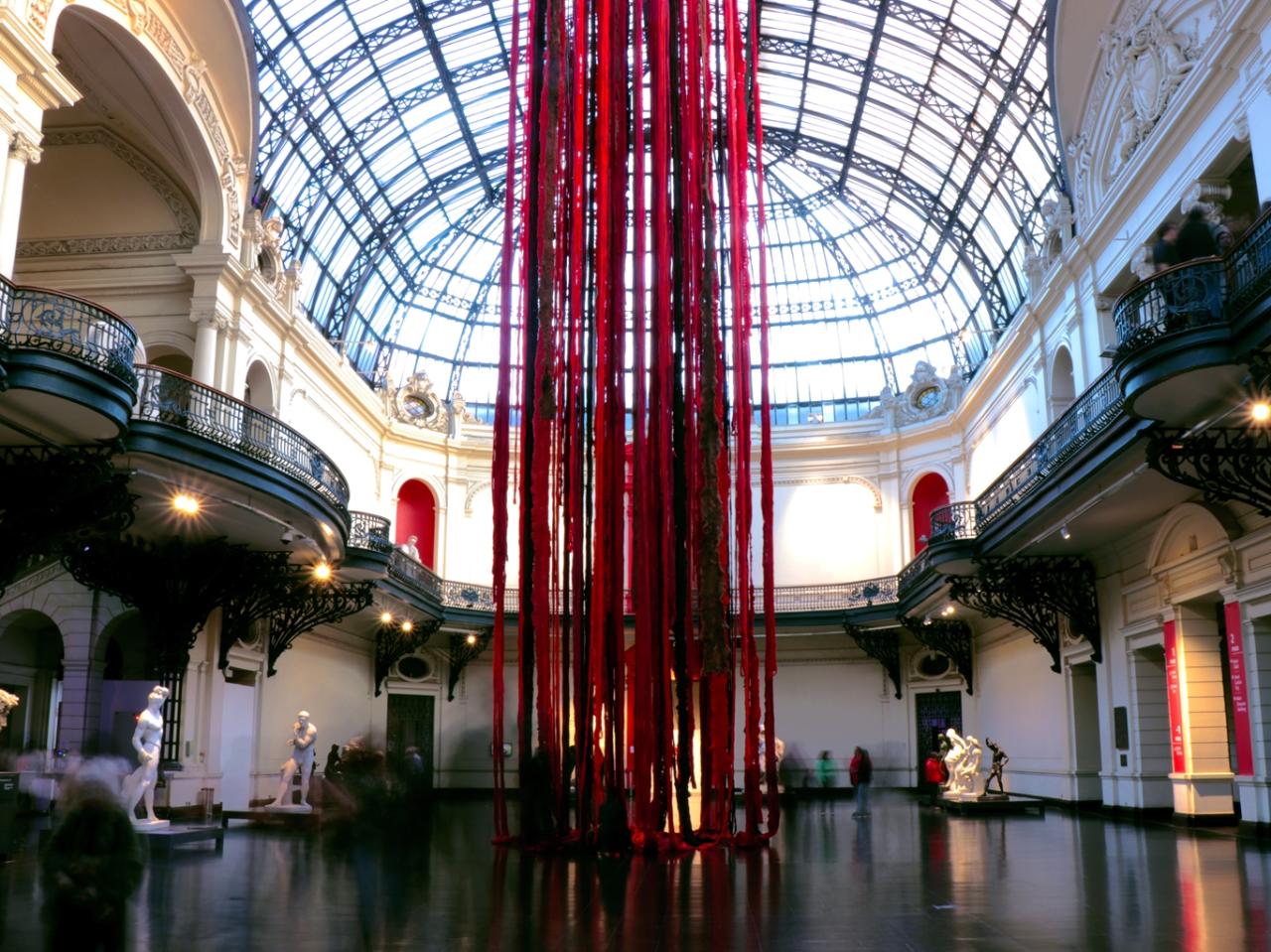 Instalación con fibras gruesas de lana roja colgando desde el techo del Museo