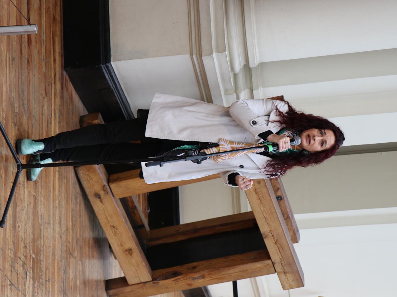 Mujer con abrigo blanco dando un discurso