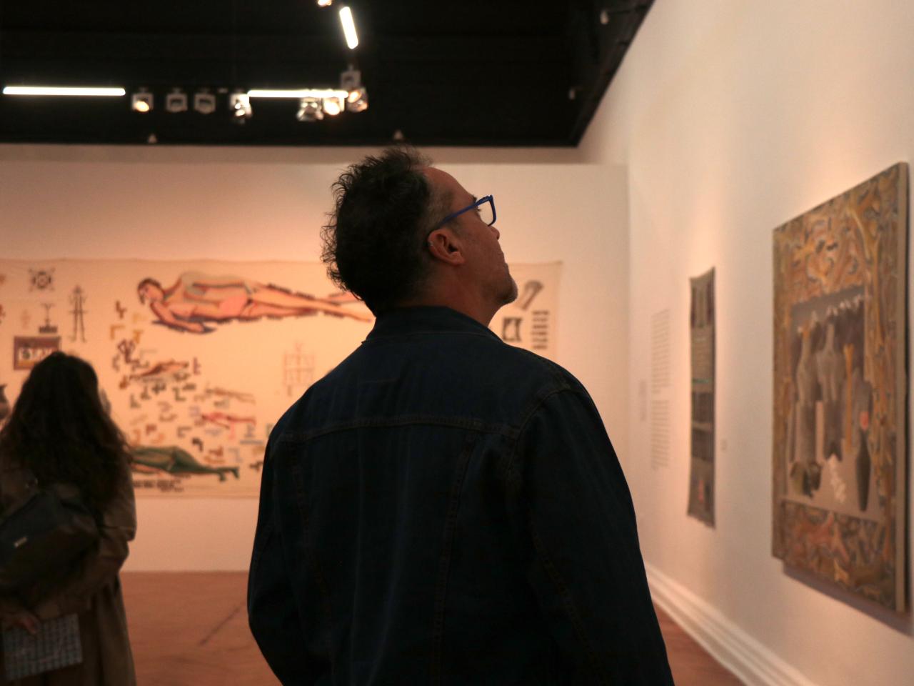 Hombre mirando cuadros en la exposición