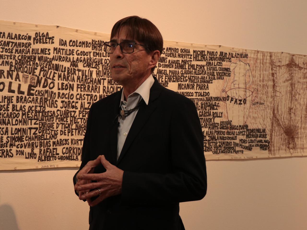 Hombre de lentes con una pieza de la exposición a su espalda