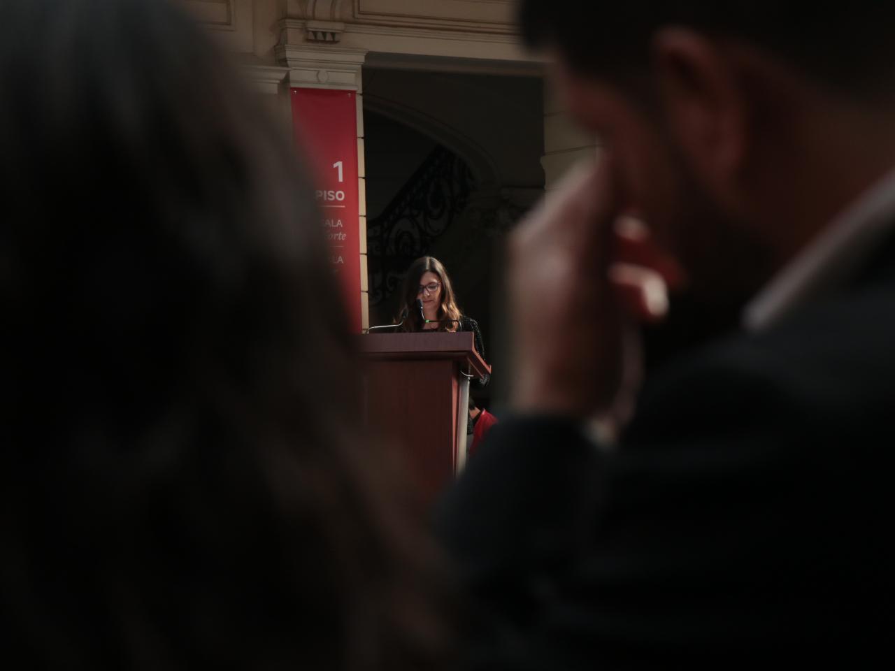 Mujer de lentes dando un discurso