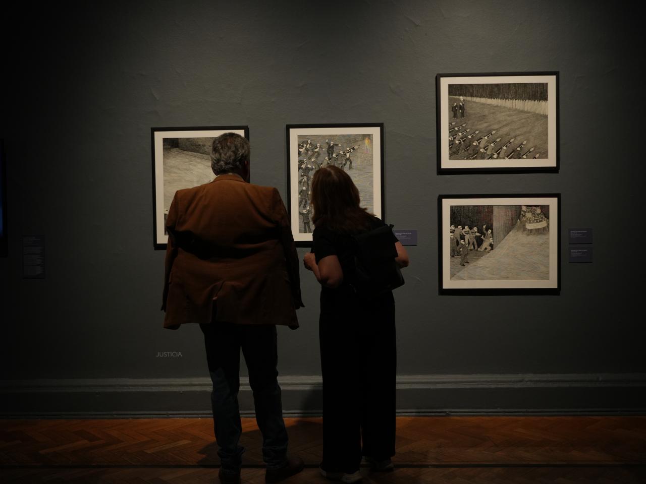 Dos personas viendo cuadros de la exposición