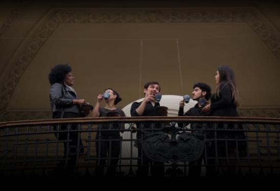 Personas conversando con tazas en uno de los balcones del Museo