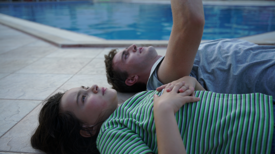 Imagen de un hombre y una niña tendidos junto a una piscina