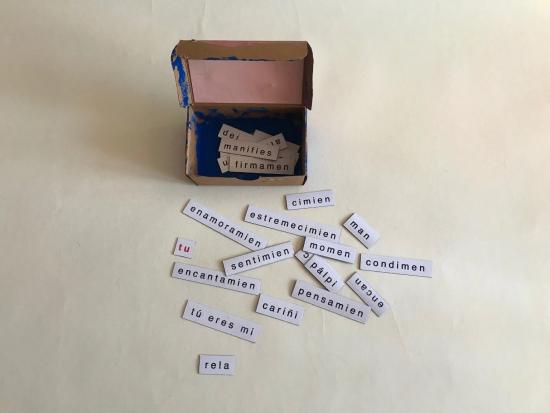 Caja de fósforos intervenida, con papeles a su alrededor que tienen diversas palabras escritas