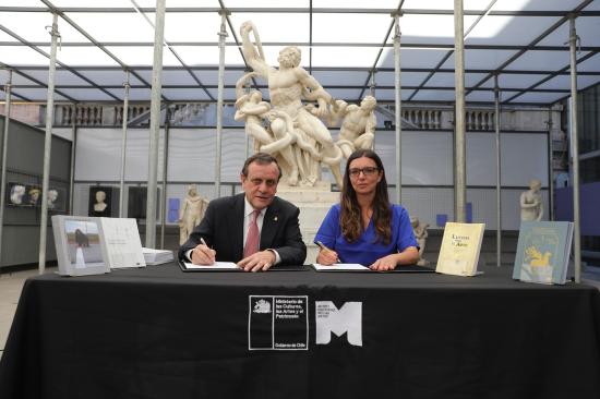 Fotografía de un hombre y una mujer sentados frente a un mesón, firmando documentos