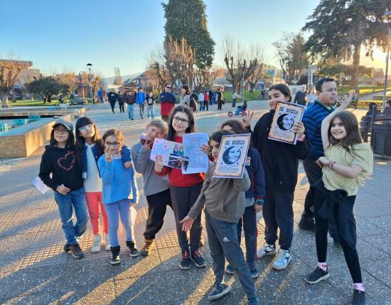 Fotografía de niñas y niños levantando carteles con el rostro de Gabriela Mistral
