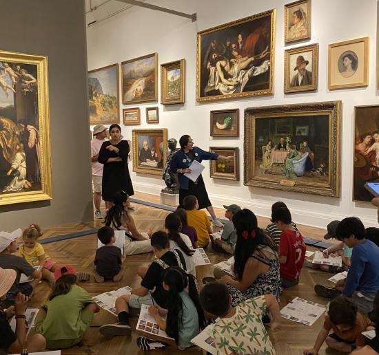 Grupo de niños sentados en piso en una sala de exposición