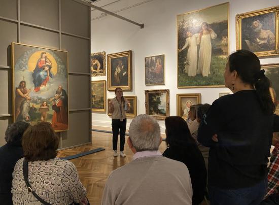 Grupo de personas observando pinturas en una exposición