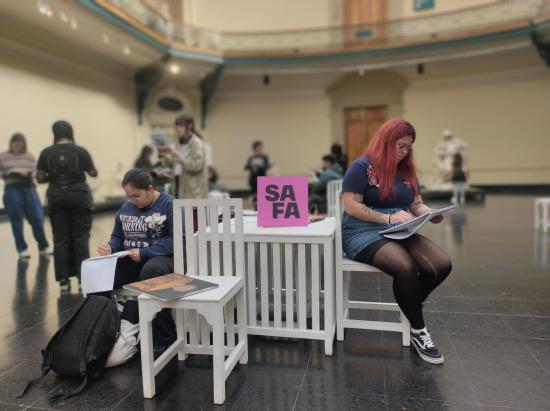 Fotografía de dos mujeres sentadas en el hall central del Museo de Bellas Artes