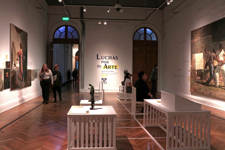 Se ve un mural en el que dice &quot;Luchas por el Arte&quot; y en la sala se encuentran mirando la exposición
