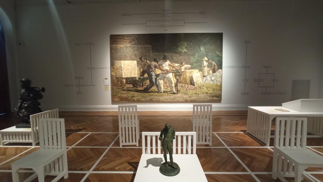 Se puede ver un cuadro que ocupa la mitad de la pared y frente a ella sillas de color blancos