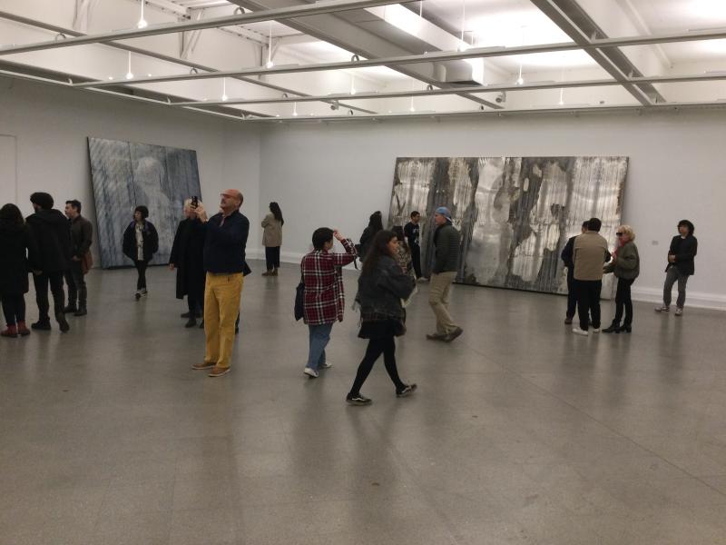 Muchas personas mirando los cuadros que se encuentran en la sala de esposición