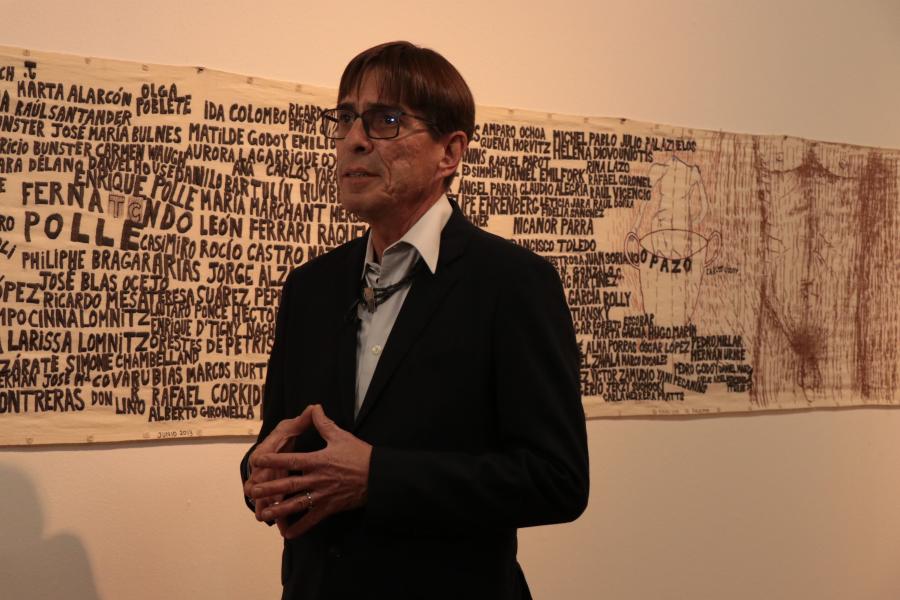 Hombre de lentes con una pieza de la exposición a su espalda