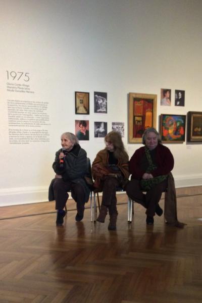 Tres mujeres mayores y a la derecha una se encuentra sosteniendo un micrófono mientras habla