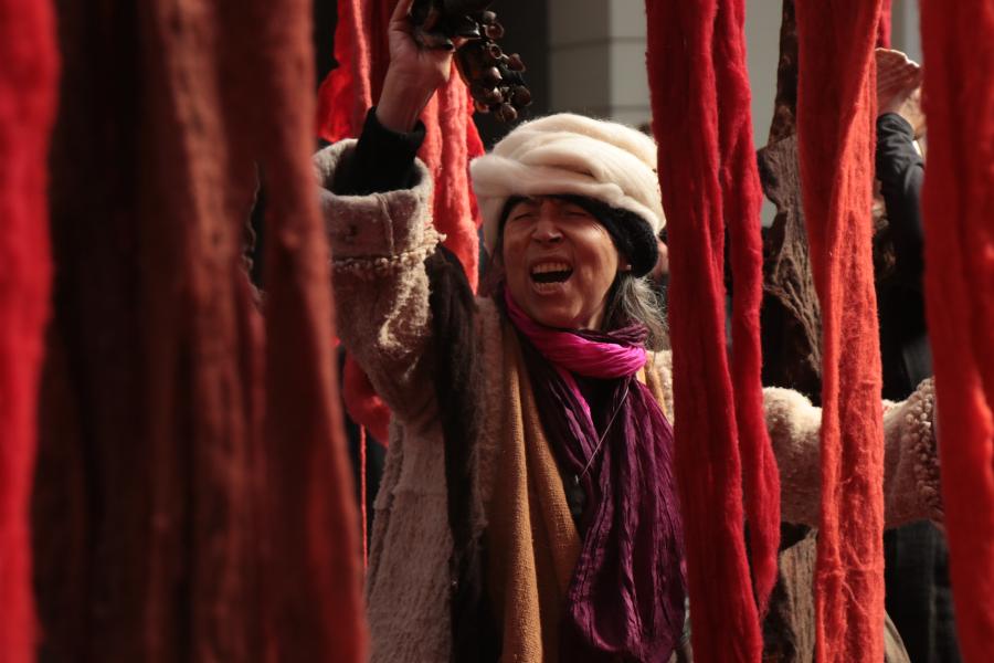 Mujer mayor riendo alrededor de telas de color rojo y naranja